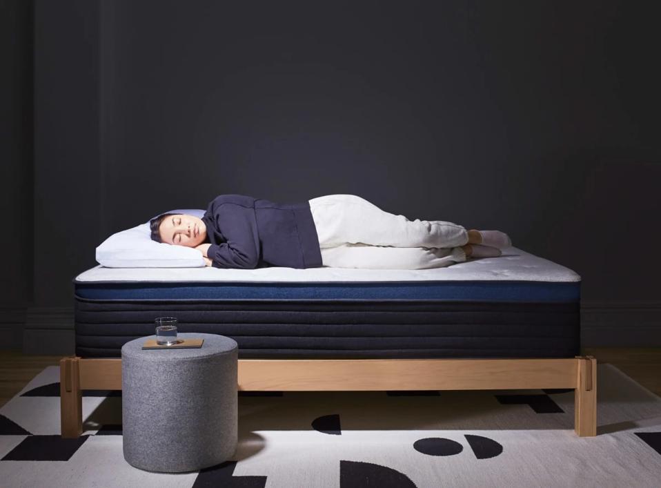 Woman sleeping on the Helix Midnight Luxe in a black room.